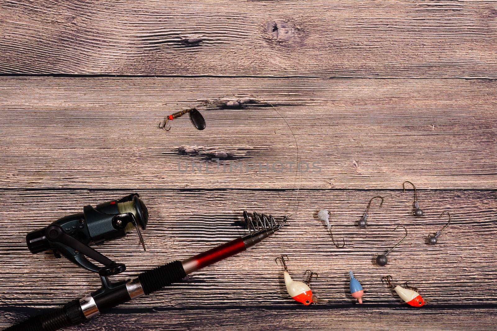 Fishing tackle - spinning, line, hooks and lures on wooden background