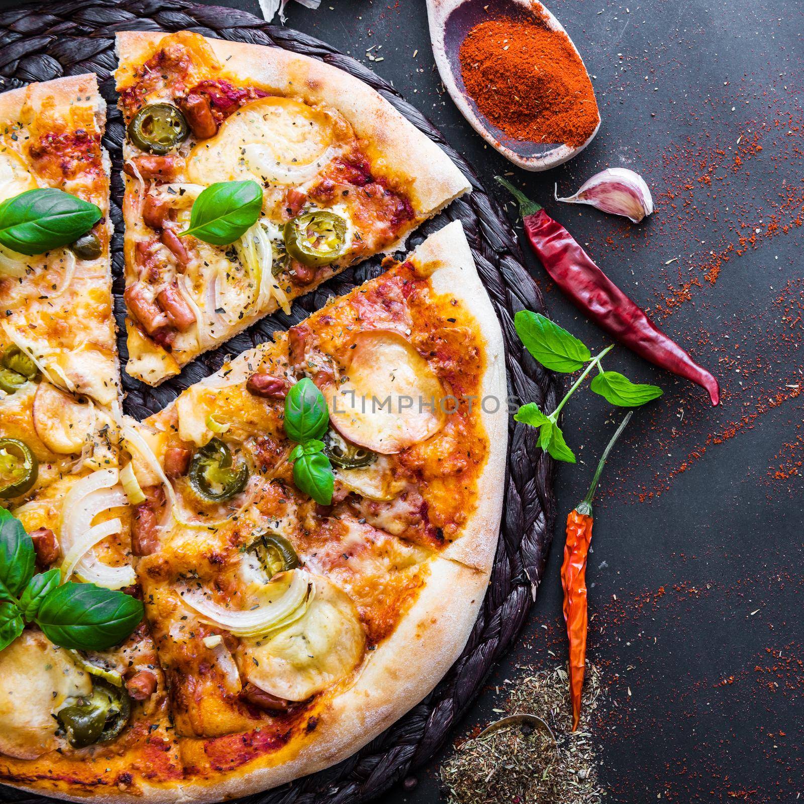 tasty pizza on a black background with spices and vegetables