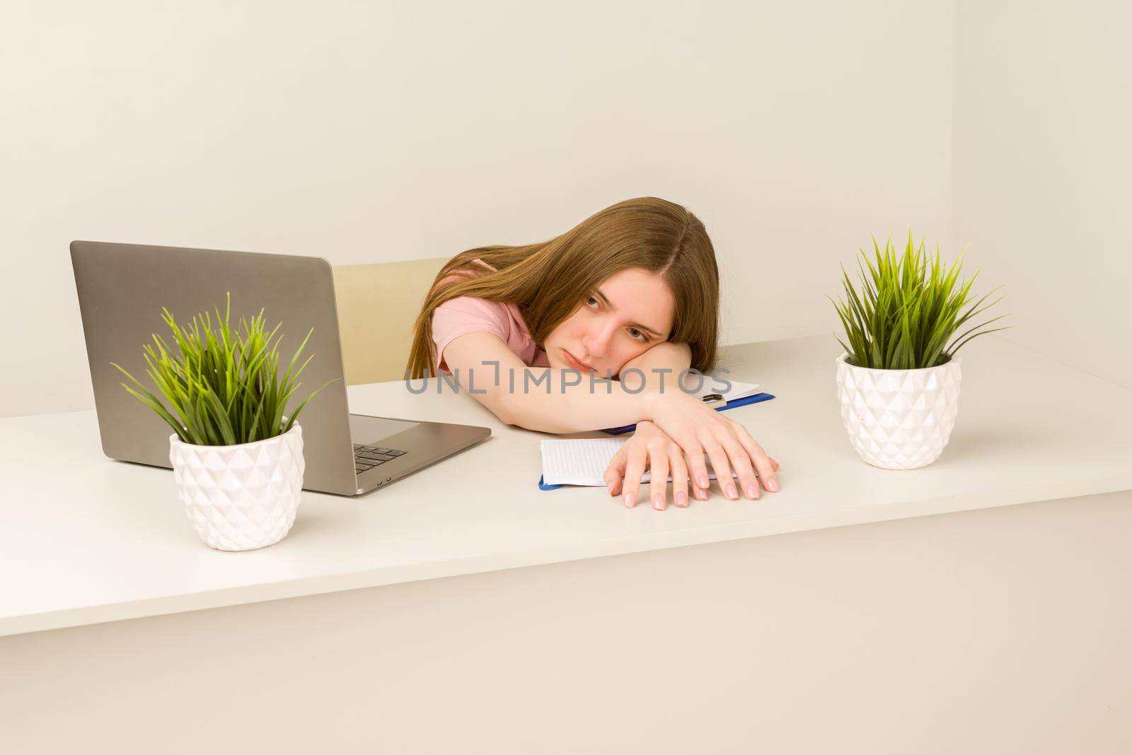 Tired overworked young intern woman working with a laptop in an office - image