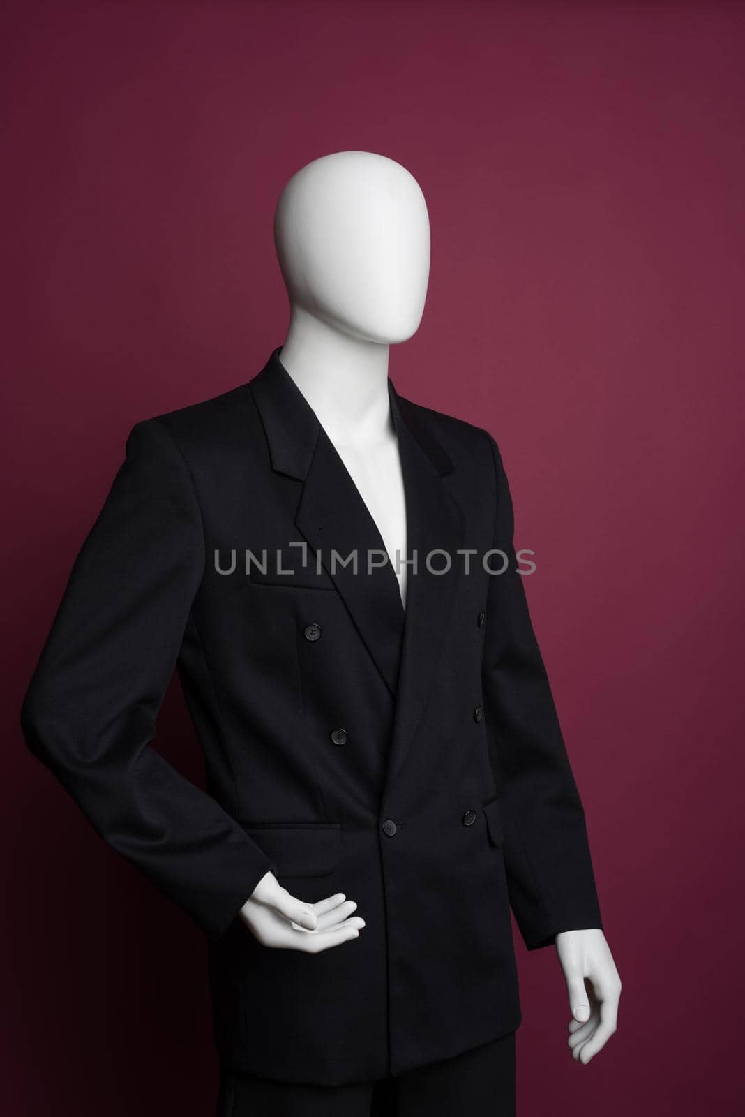 White male mannequin in a black business suit on a ruby background - image