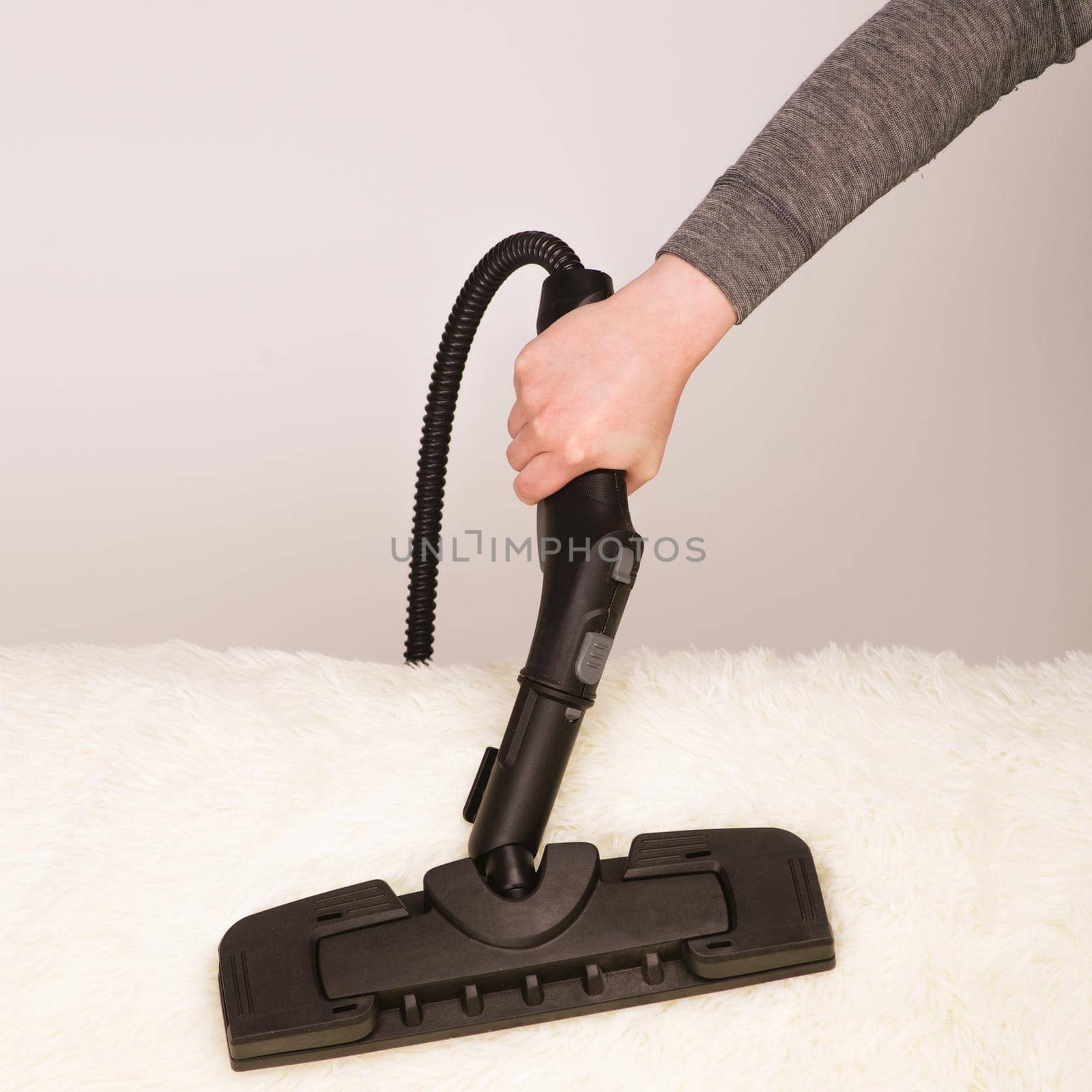 Young woman with a steam cleaner cleans the carpet on the couch - Image