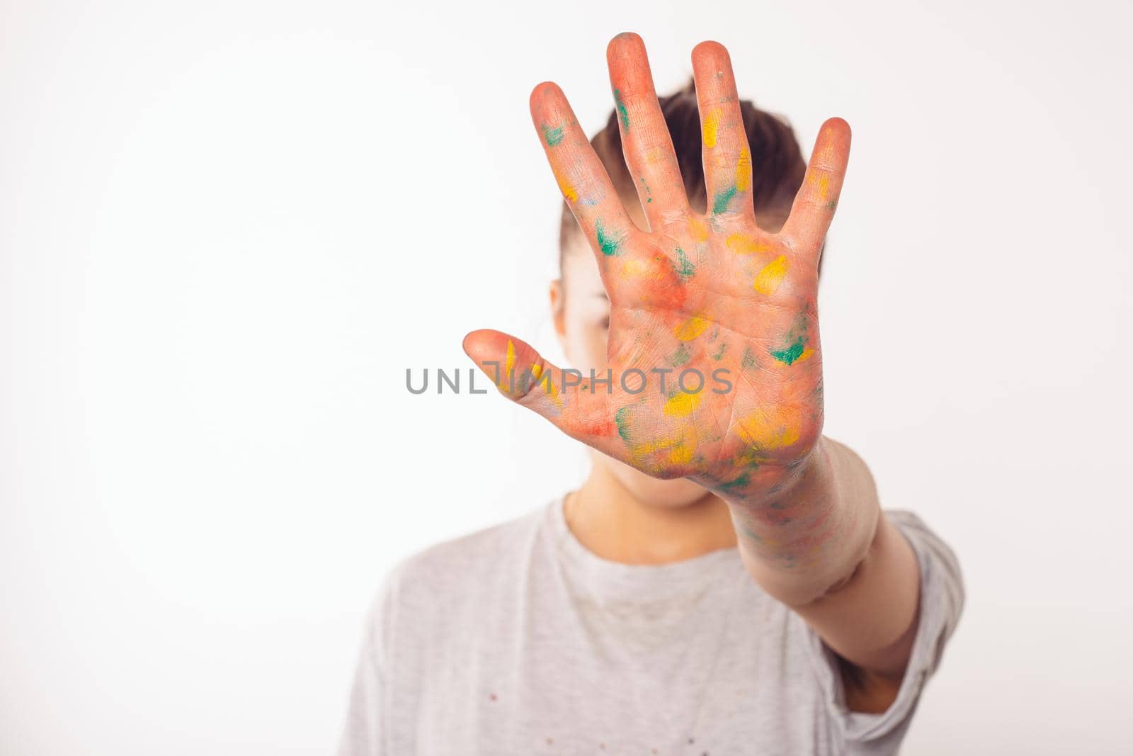 teenage girl covers her face with her right palm in paint
