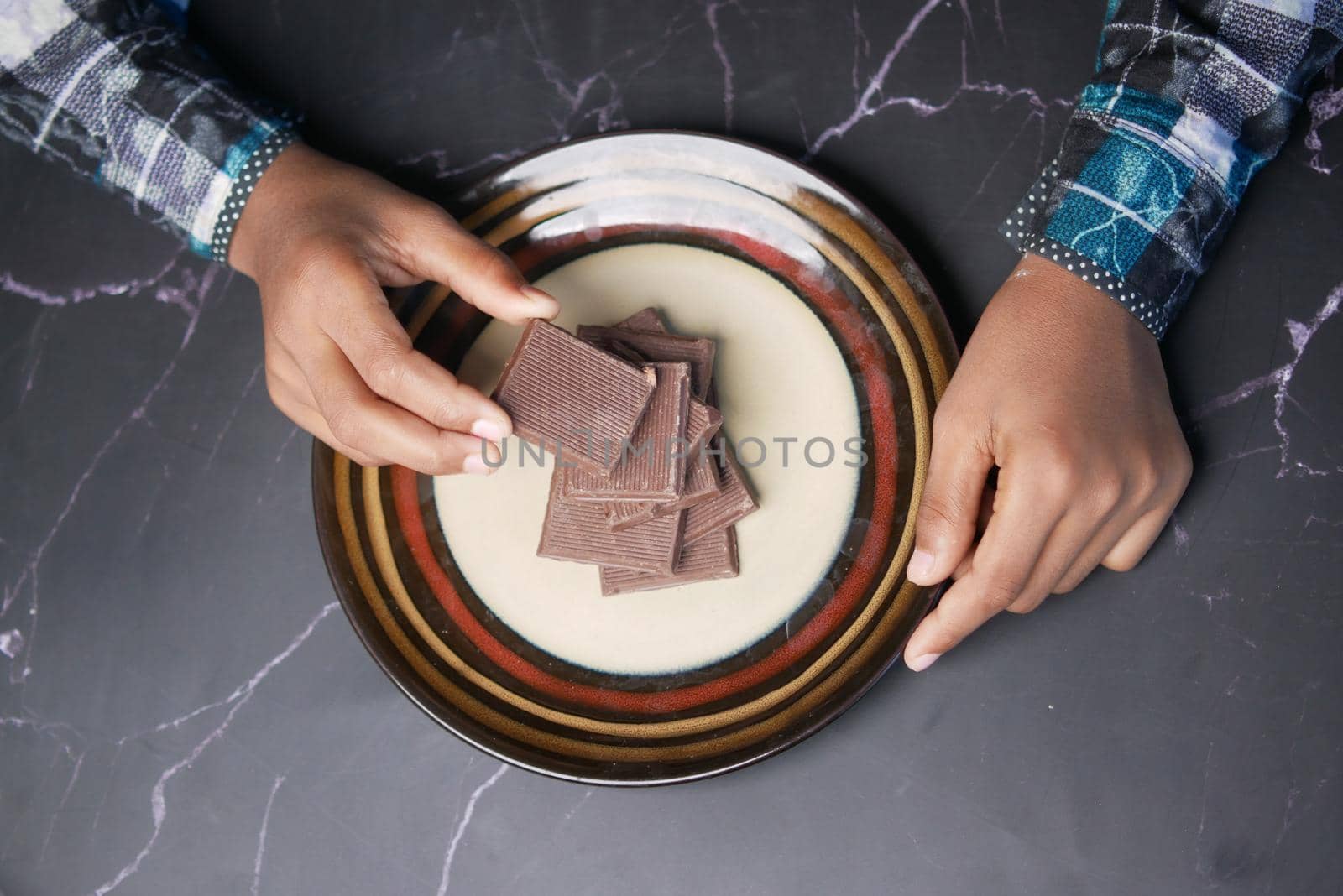 child boy hand pick dark chocolate on a plate .