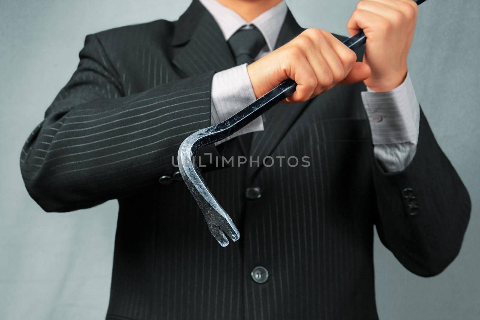 Businessman in a suit holds metal crowbar, focus on crowbar