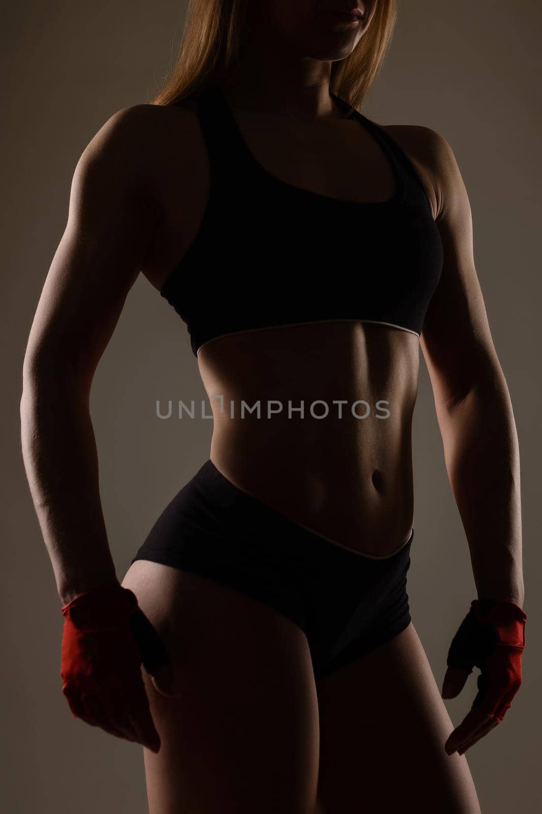 Silhouette bodybuilding girl in sports gloves for fitness posing on background