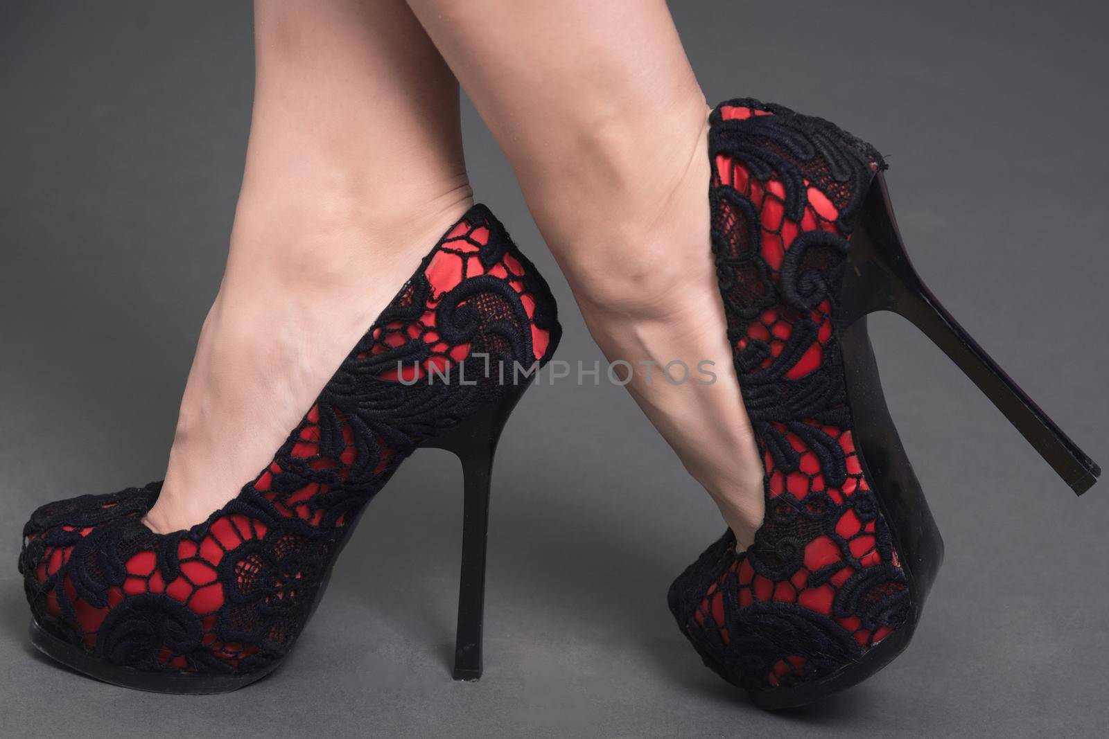 women's legs in red lace shoes with high black heels by zartarn