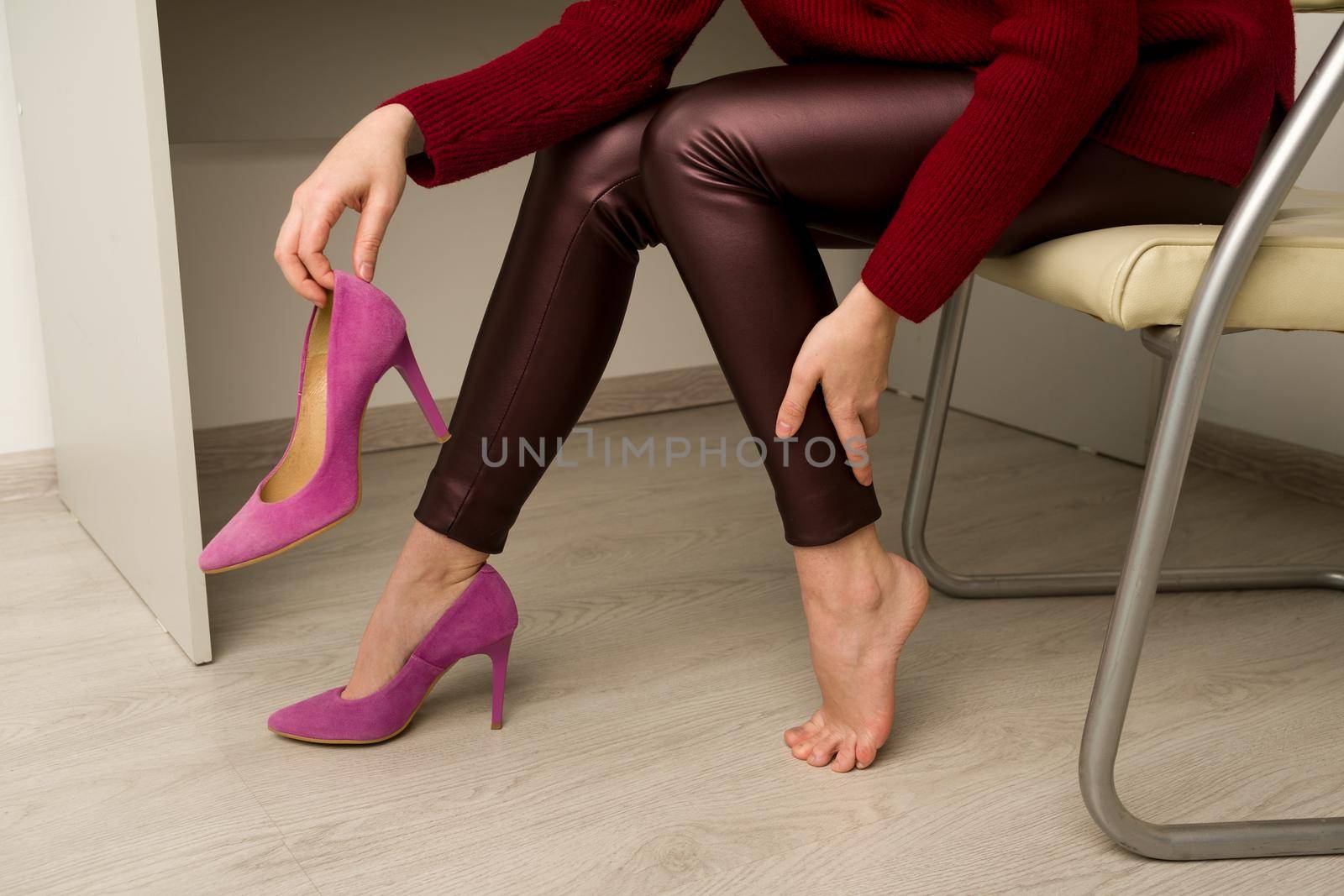 Woman suffering from leg pain in office. She rubbed terrible calluses from uncomfortable high-heeled shoes
