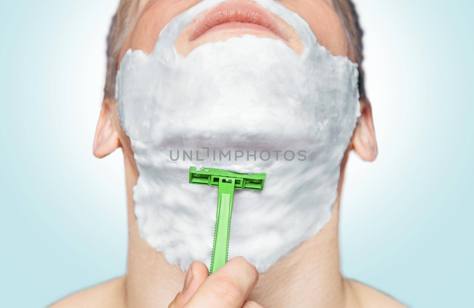 Man is shaving with green razor by alexAleksei