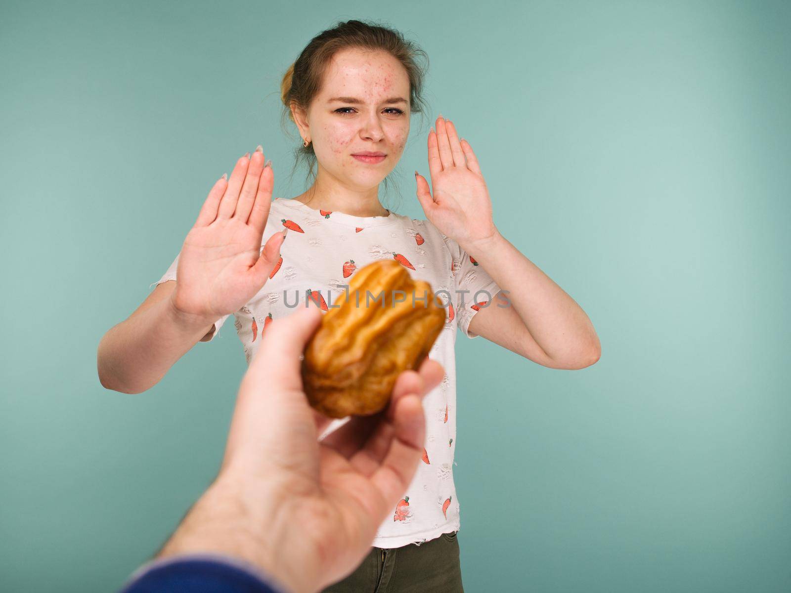Portrait of pimply teen girl hows hands stop on a delicious cake on blue background
