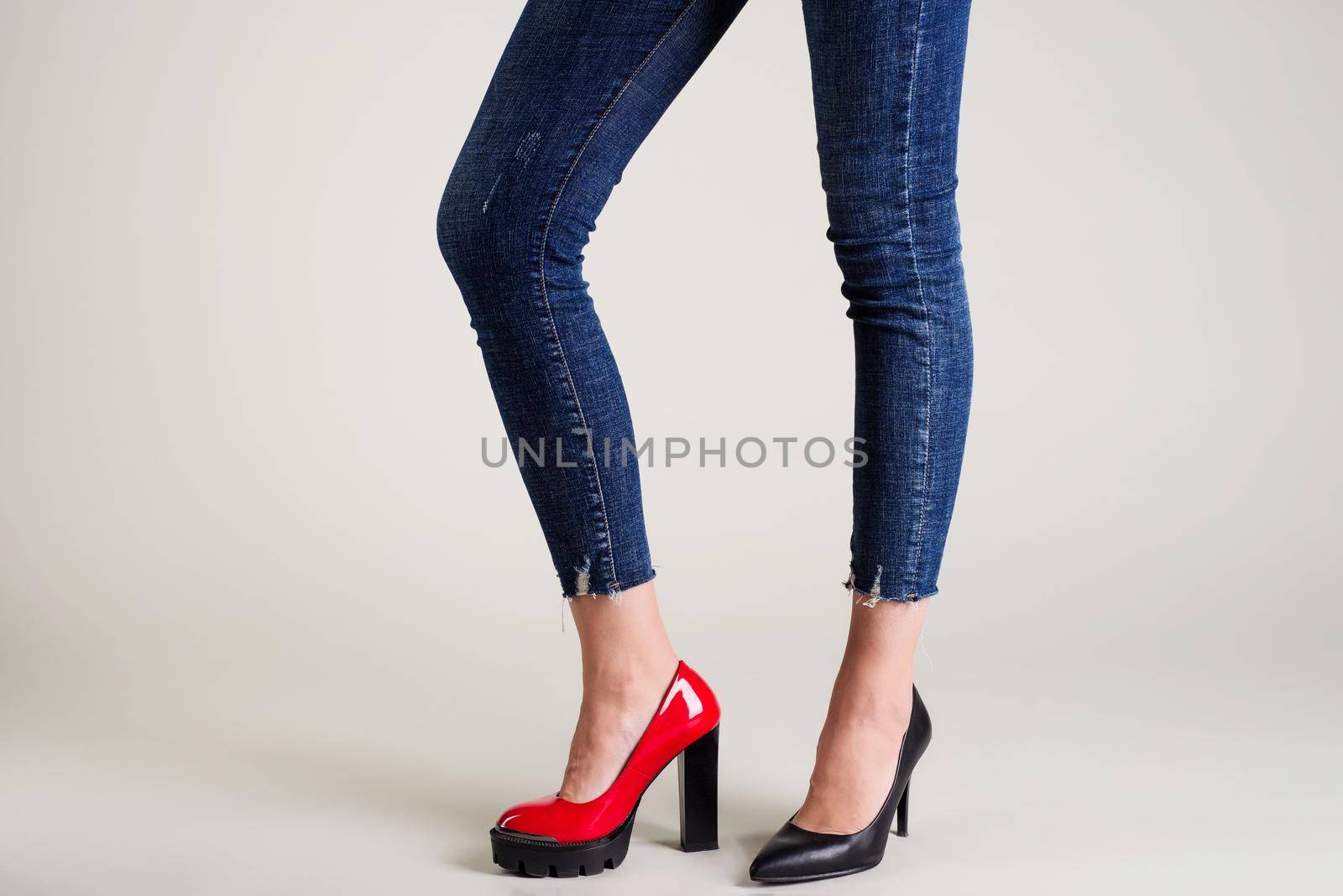 Woman legs in summer shoes isolated over neutral background. select your pair concept - red or black shoes