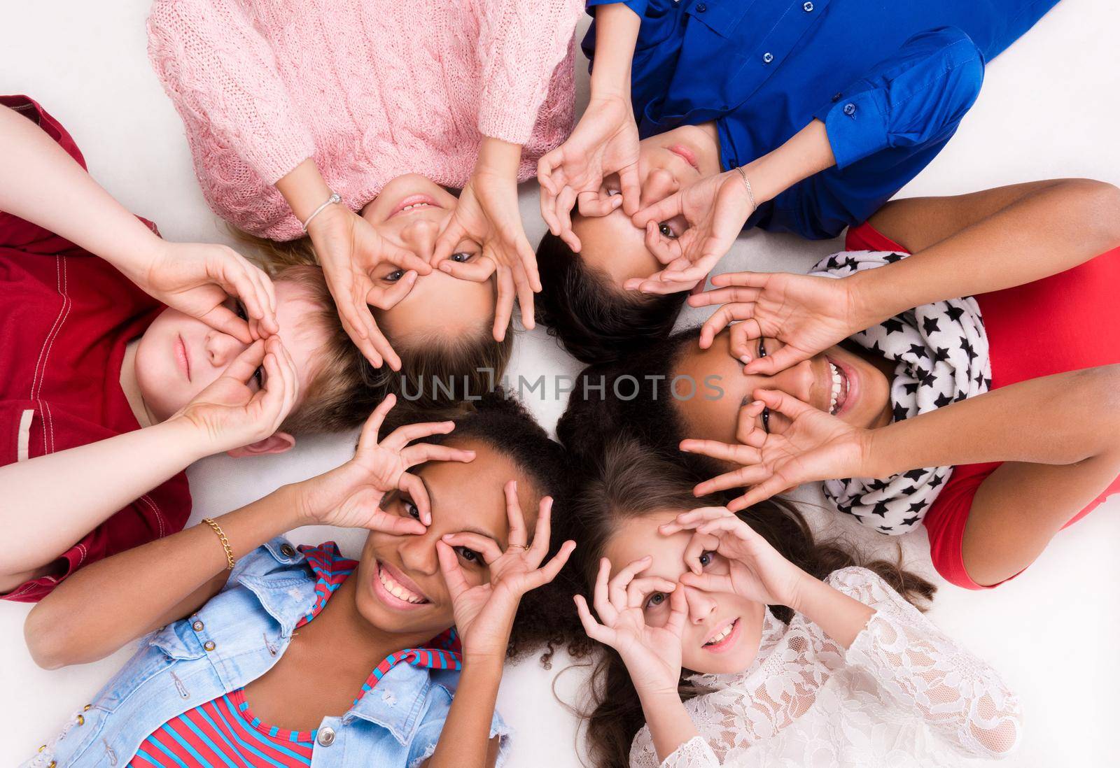 teenage children lying on the floor head to head with glasses out of fingers