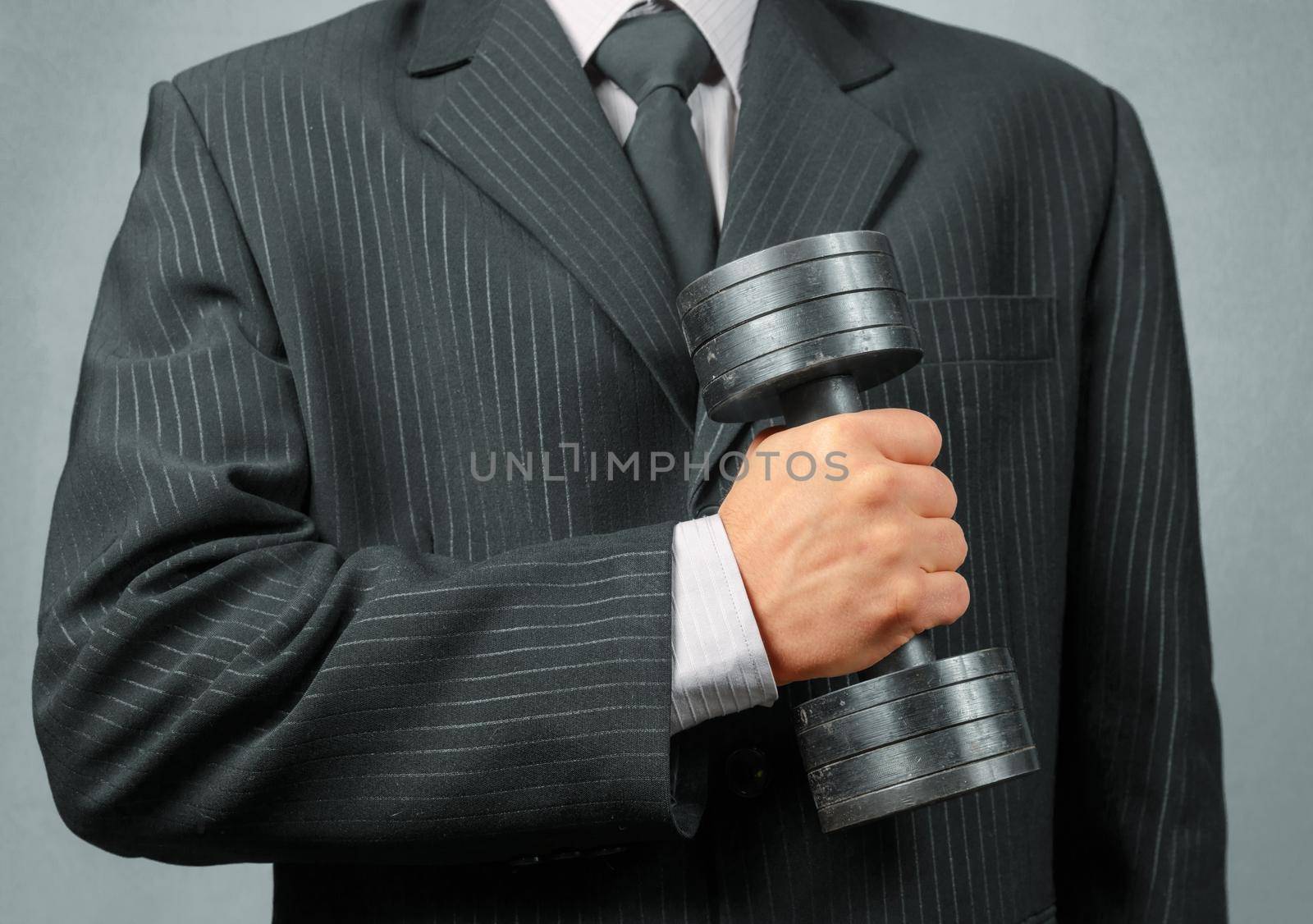 Businessman holds metal dumbbell by alexAleksei