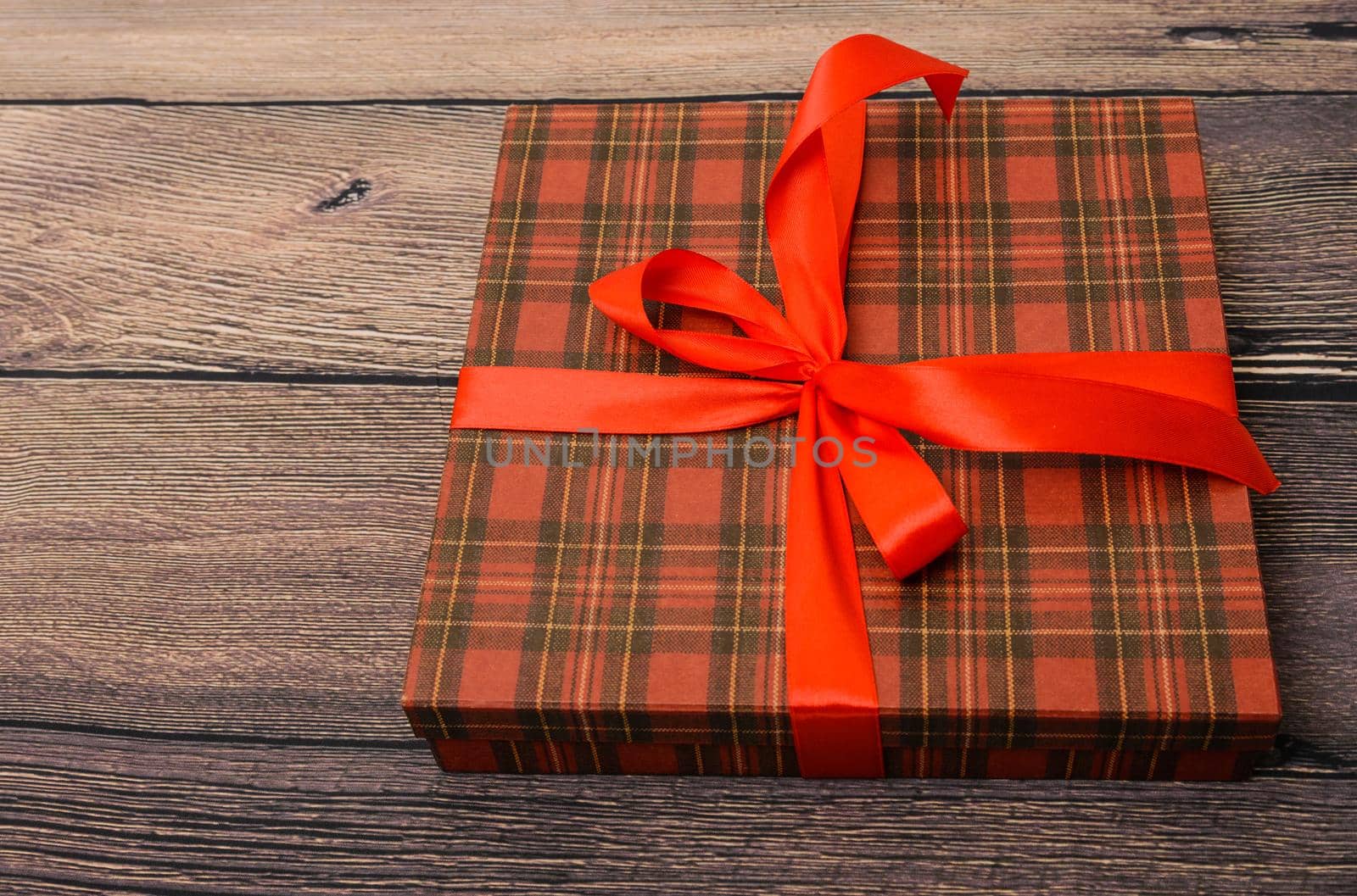 Small gift box with red ribbon on wooden table