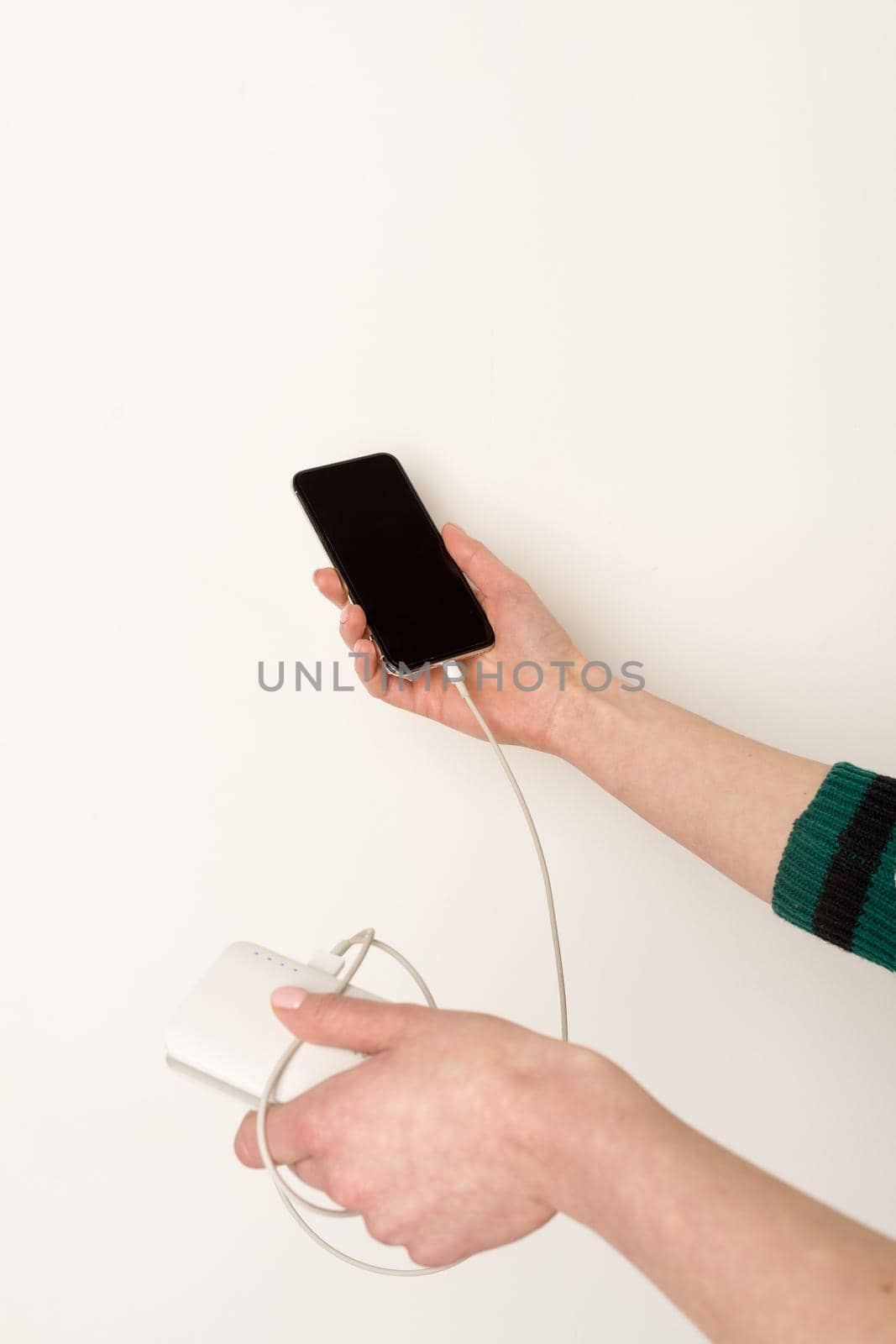 emale hands holding and using smartphone while charging power bank by zartarn