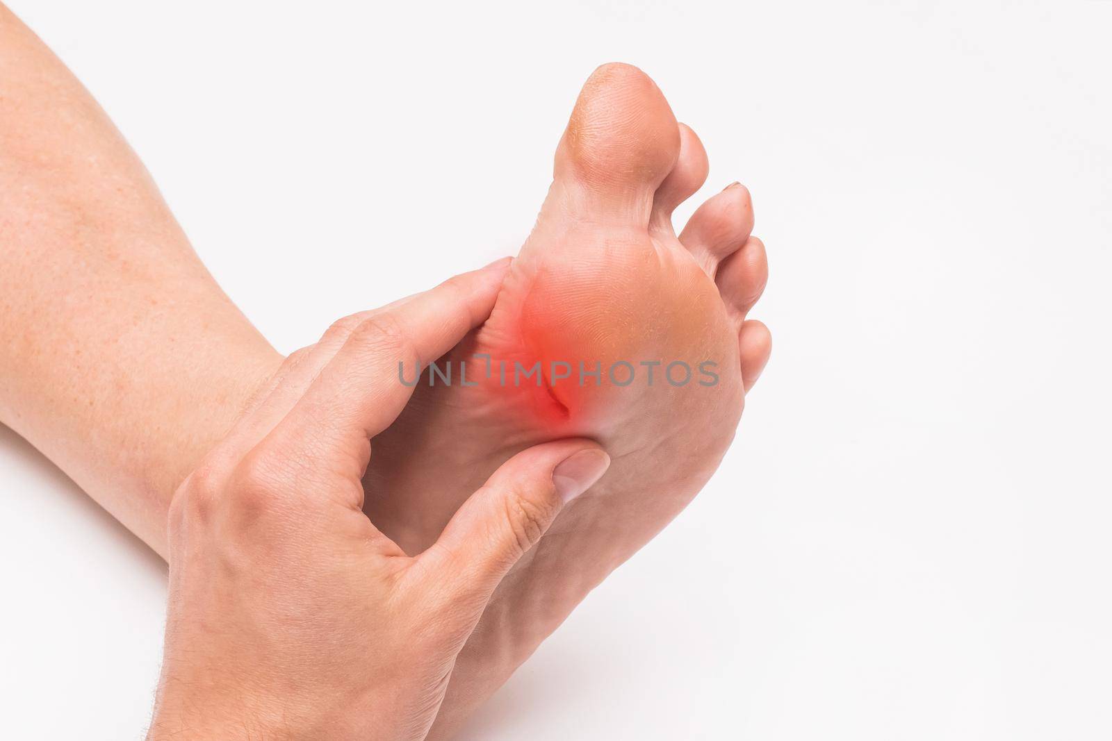 A doctor's hand touches and examines the wound on the foot of an elderly woman on a white background. Medical concept.