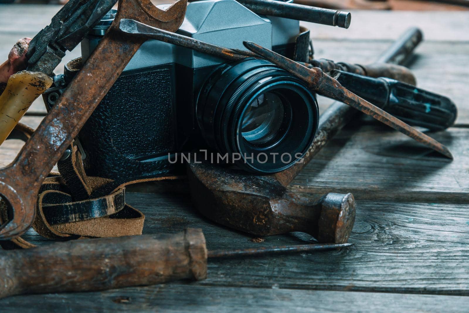 Old working tools and retro photo camera on wooden table. With a vintage retro filter. Dark picture tone.
