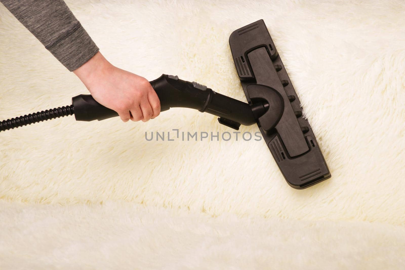 Young woman with a steam cleaner cleans the carpet on the couch - Image