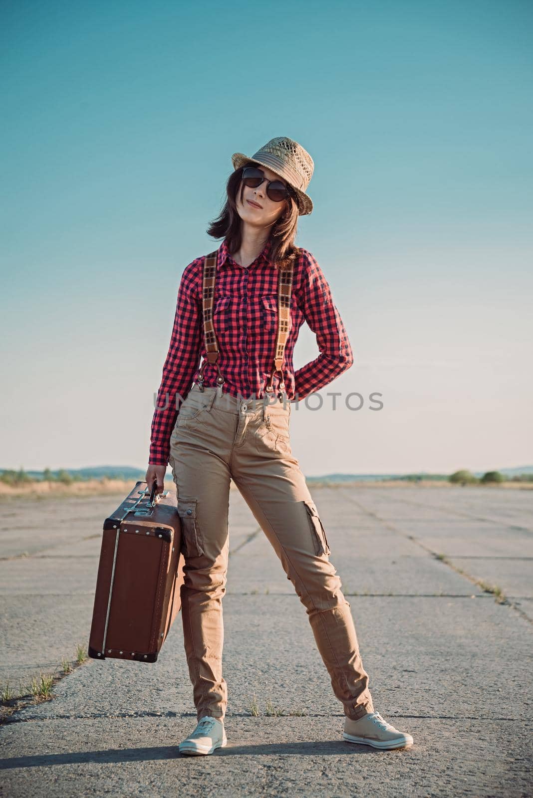 Young hipster woman holds vintage suitcase on the roa