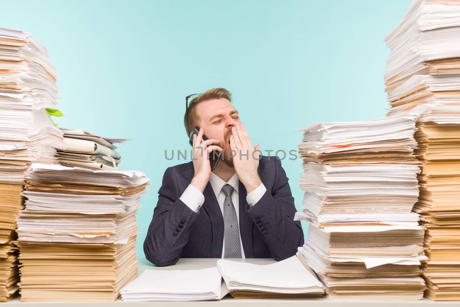 Close-up image of a stressful businessman tired from his work on the foreground - image