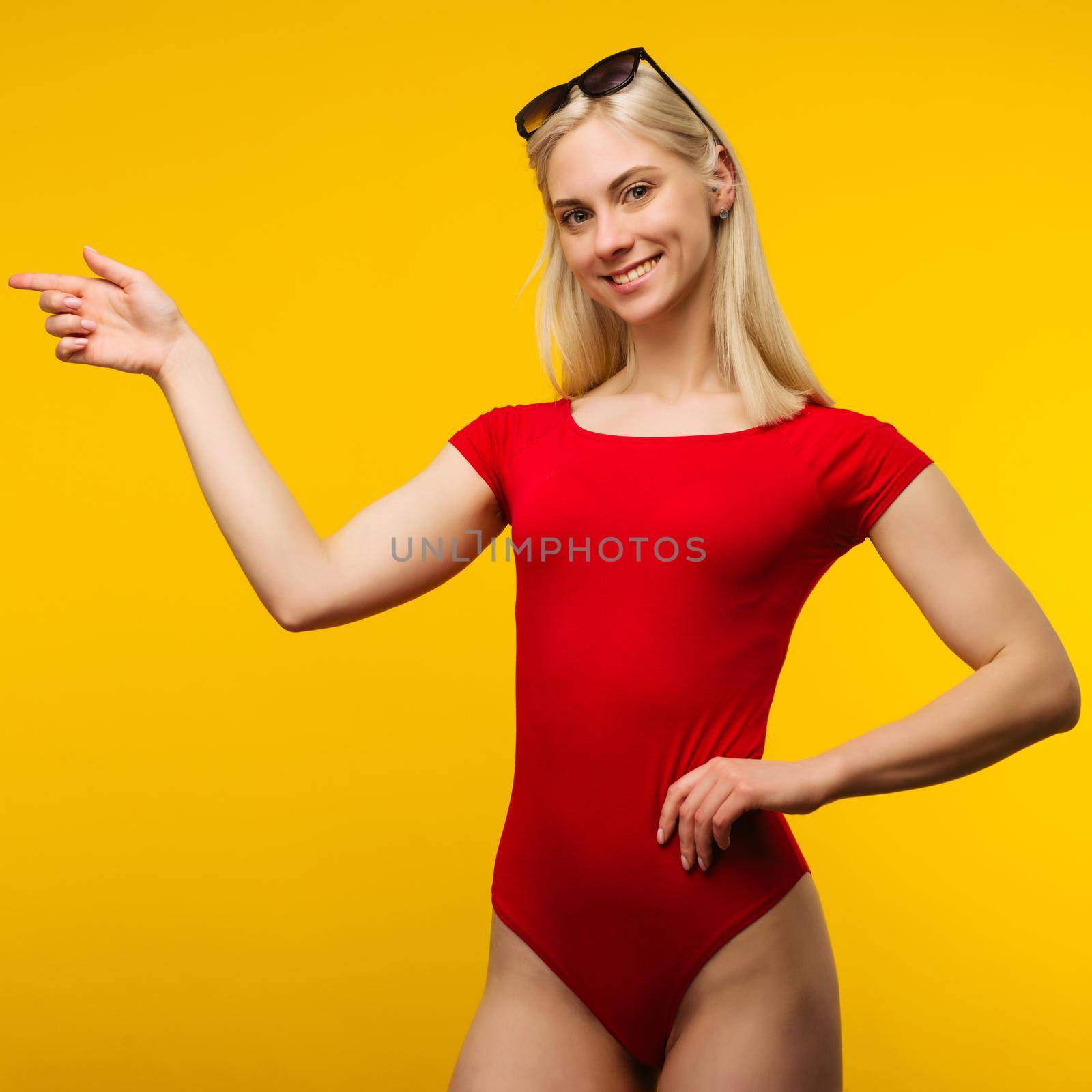 pretty blond lifeguard in red swimsuit and sunglasses points finger by zartarn