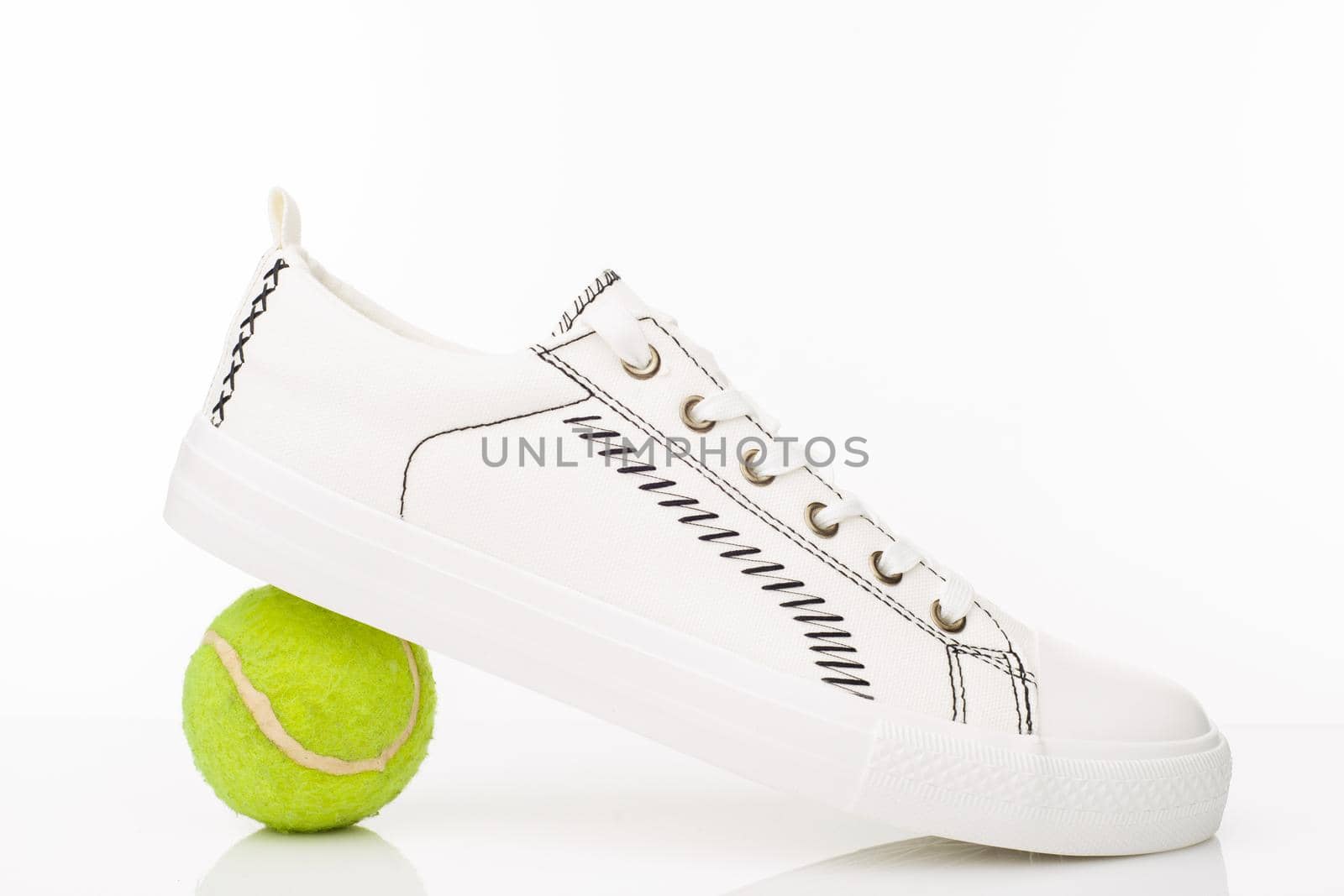 Fashionable white walking shoes with tennis ball on a white background. - image