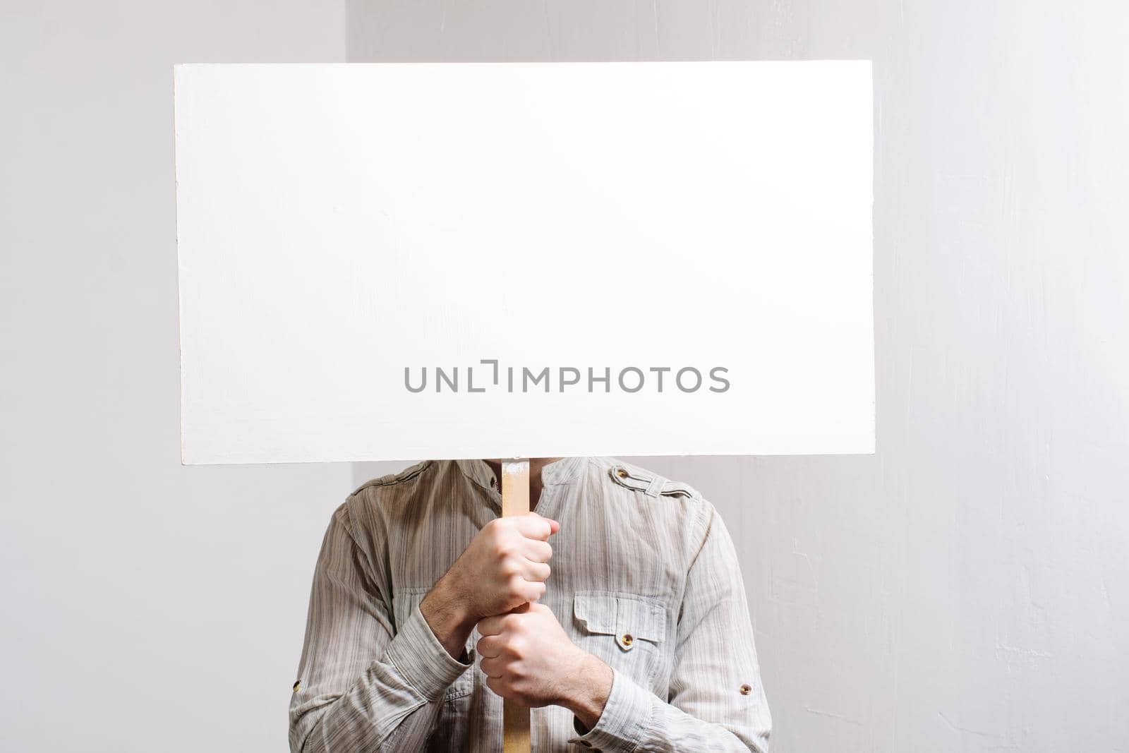 Working in a cap holding a banner over his head at white wall