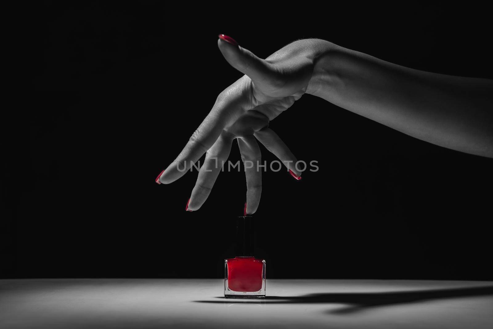 Hand with red manicure and nail polish bottle. black and white