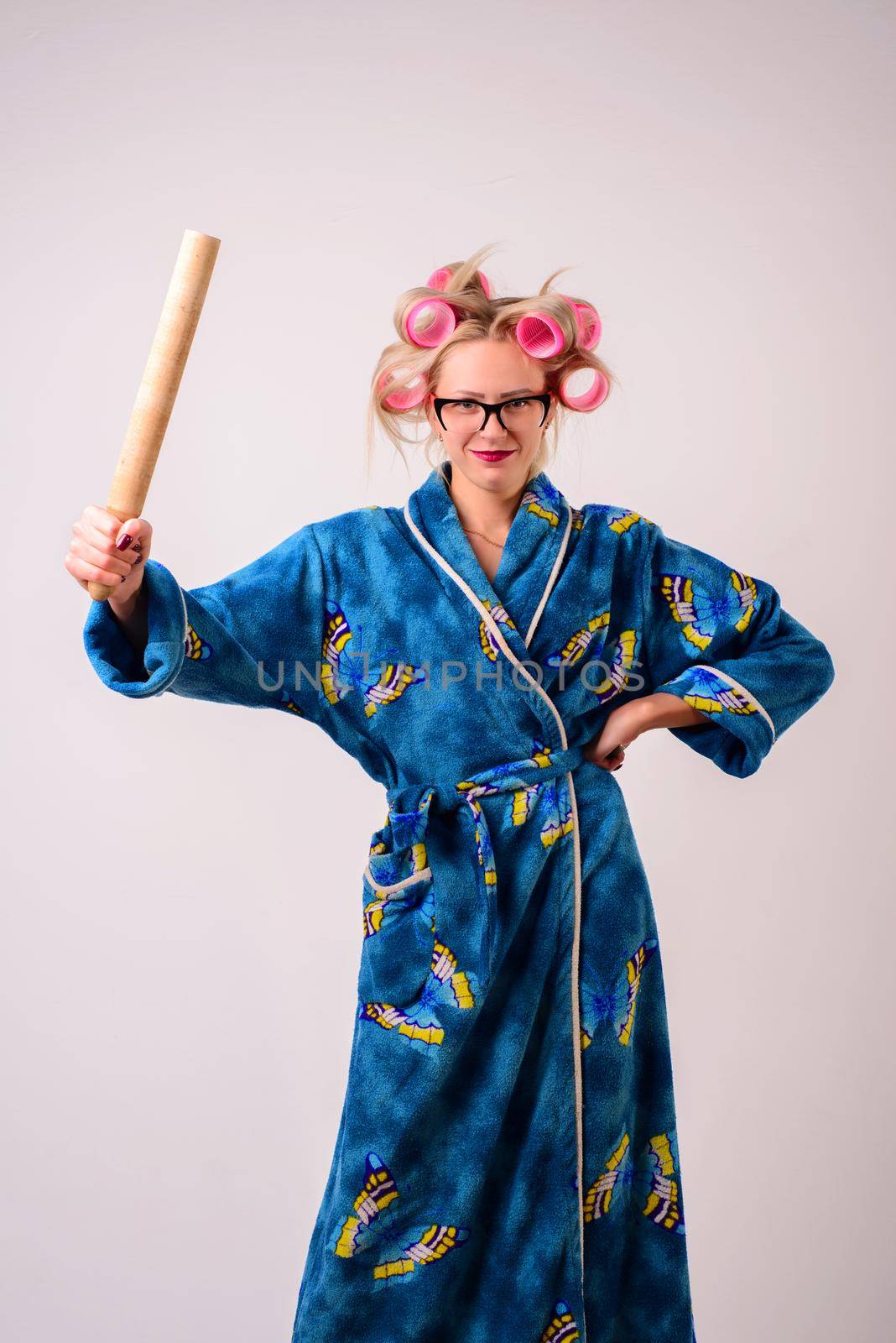 smiling woman housewife in a dressing gown and curlers with a ladle in her hand.