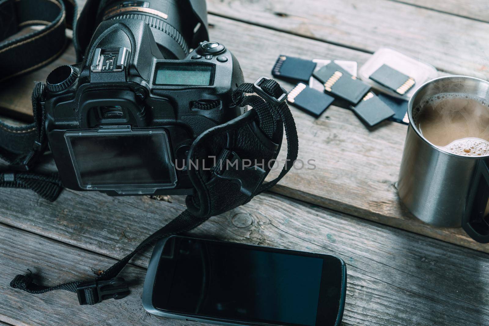 Digital photo camera, memory cards and mobile phone on wooden table