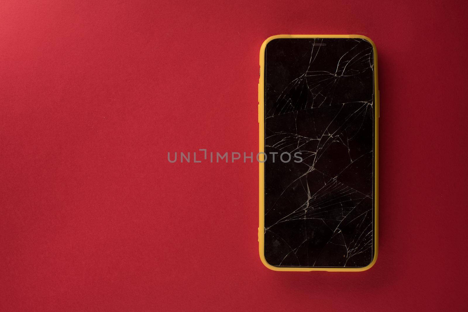 Smartphone with broken screen on red background - image