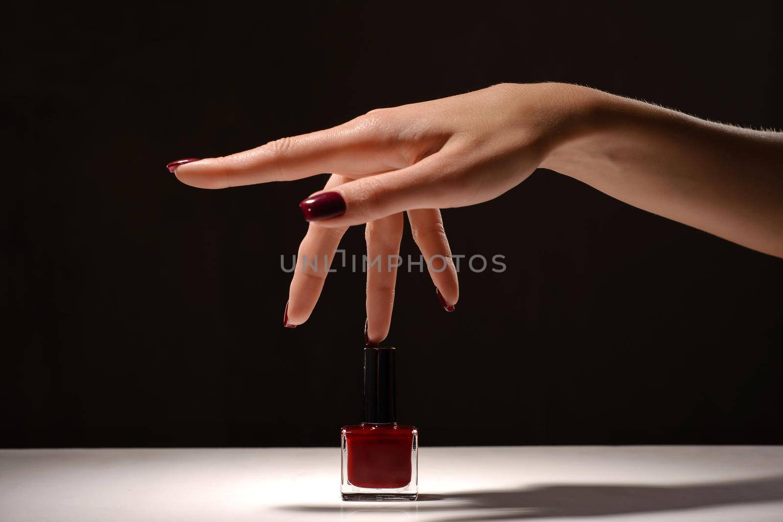 Female hand with red manicure and nail polish bottle. black and white