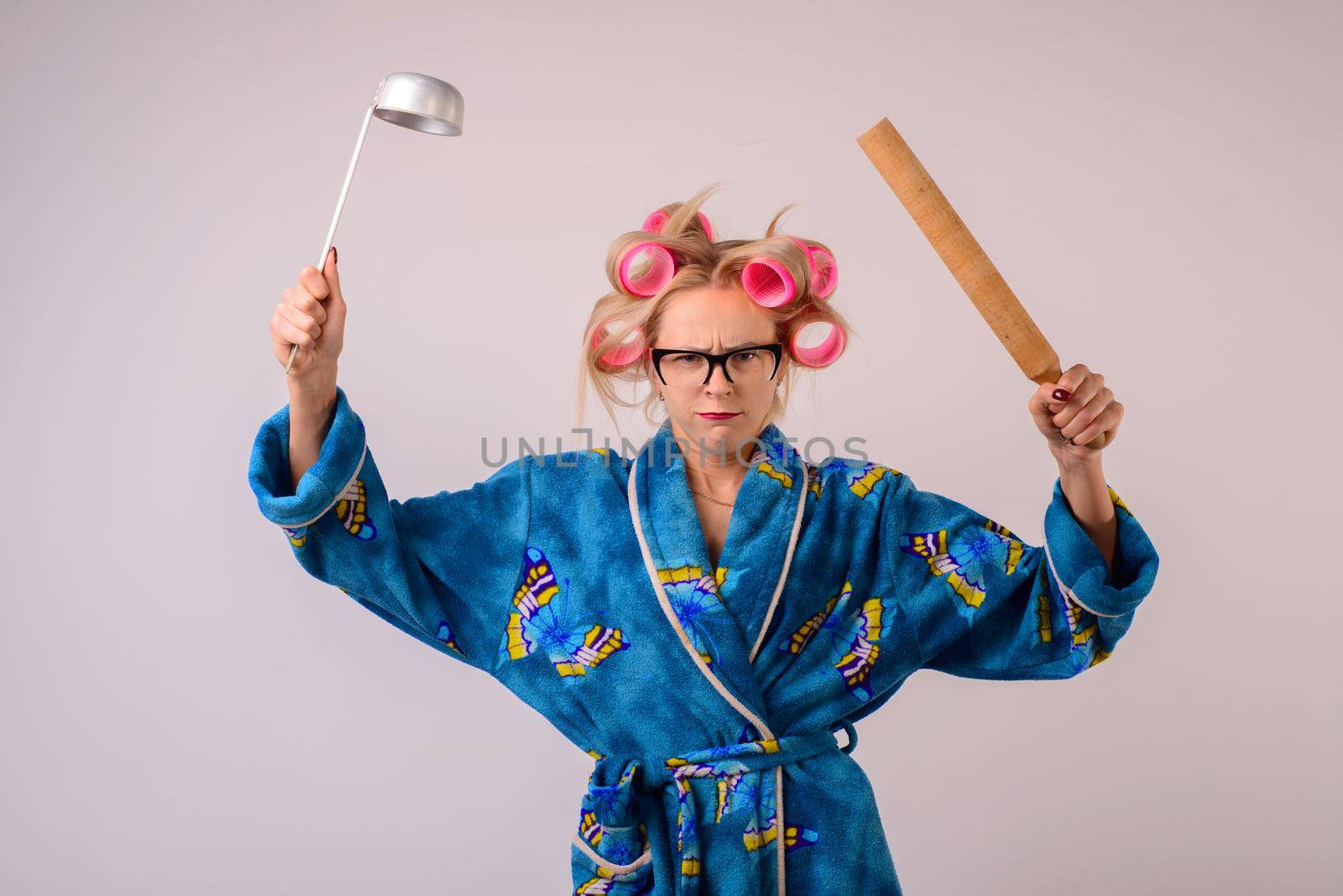harsh housewife in a dressing gown and curlers with a ladle in her hand.