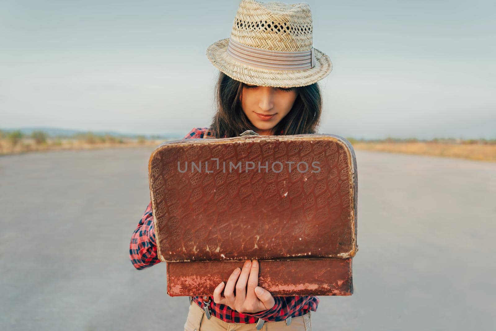 Young beautiful woman looking for something in the open suitcase, theme of travel