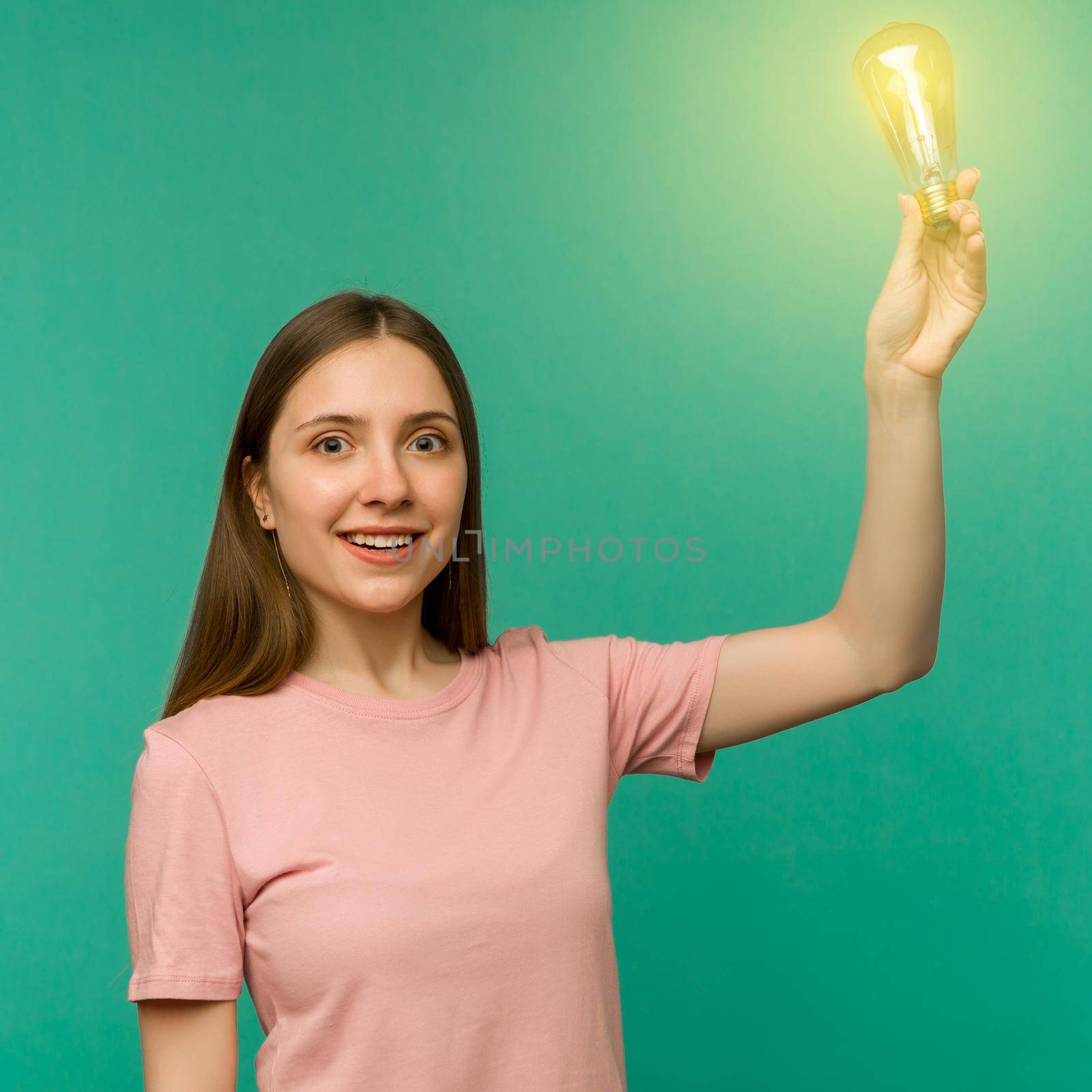 Cute girl student holds a lamp in her hand isolated on a background. The concept of an idea or creative insight.