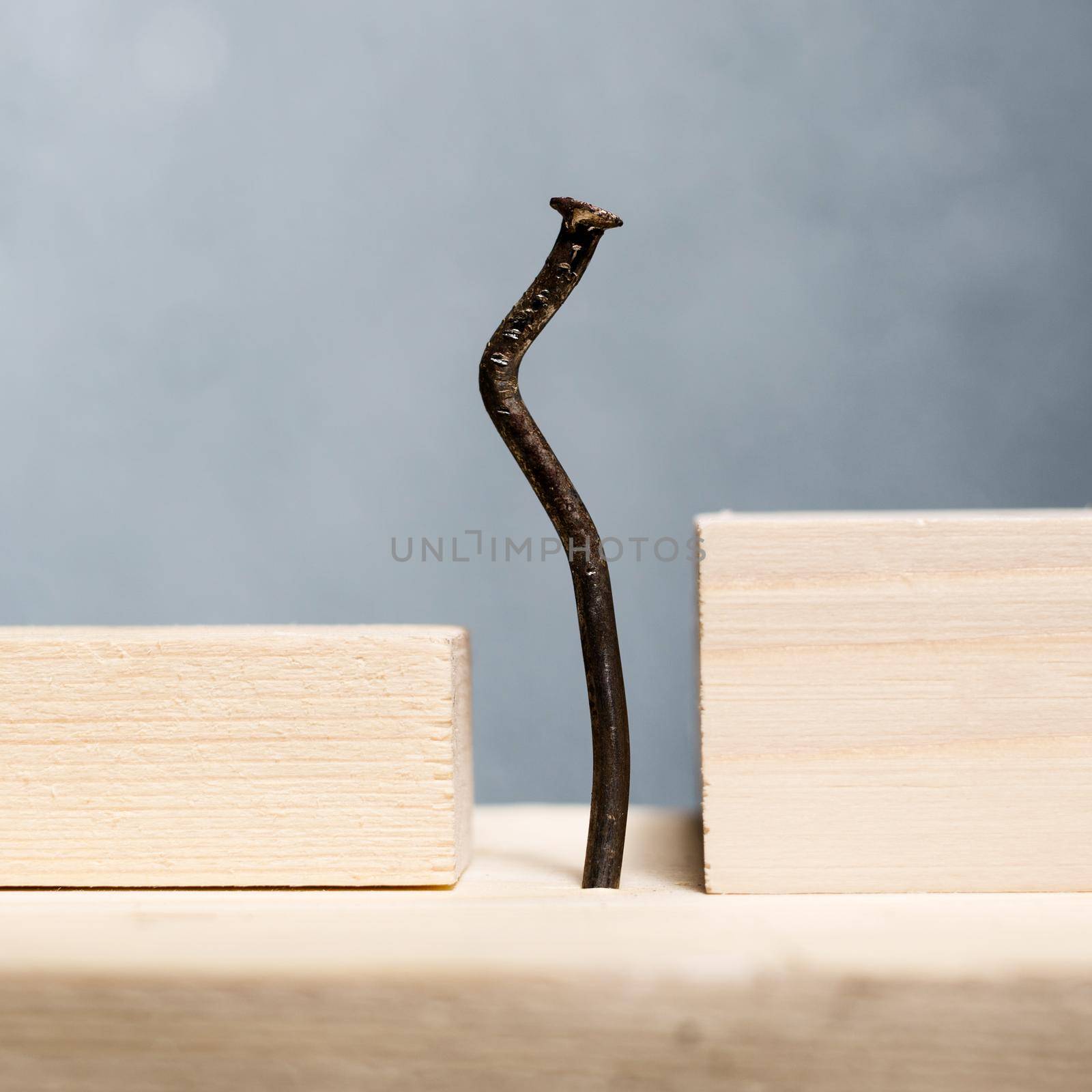 Wooden blocks and bent nail. Office worker slouching concept. - image