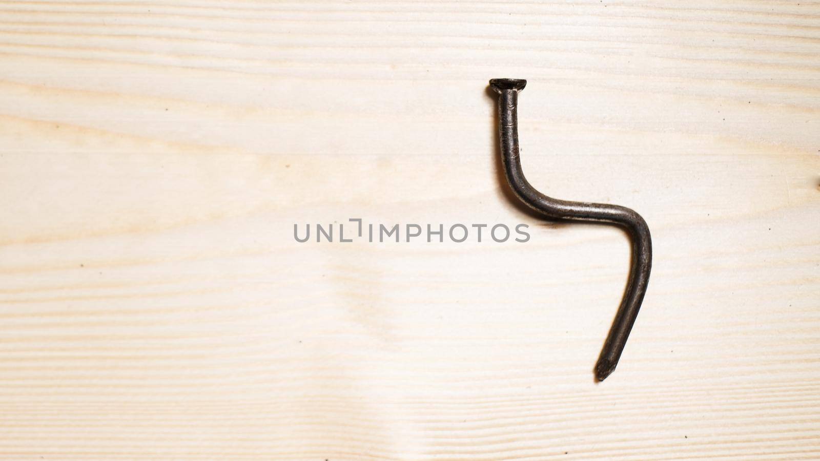 bent nail on a wooden board. Concept stoop, sciatica and degenerative disc disease - image