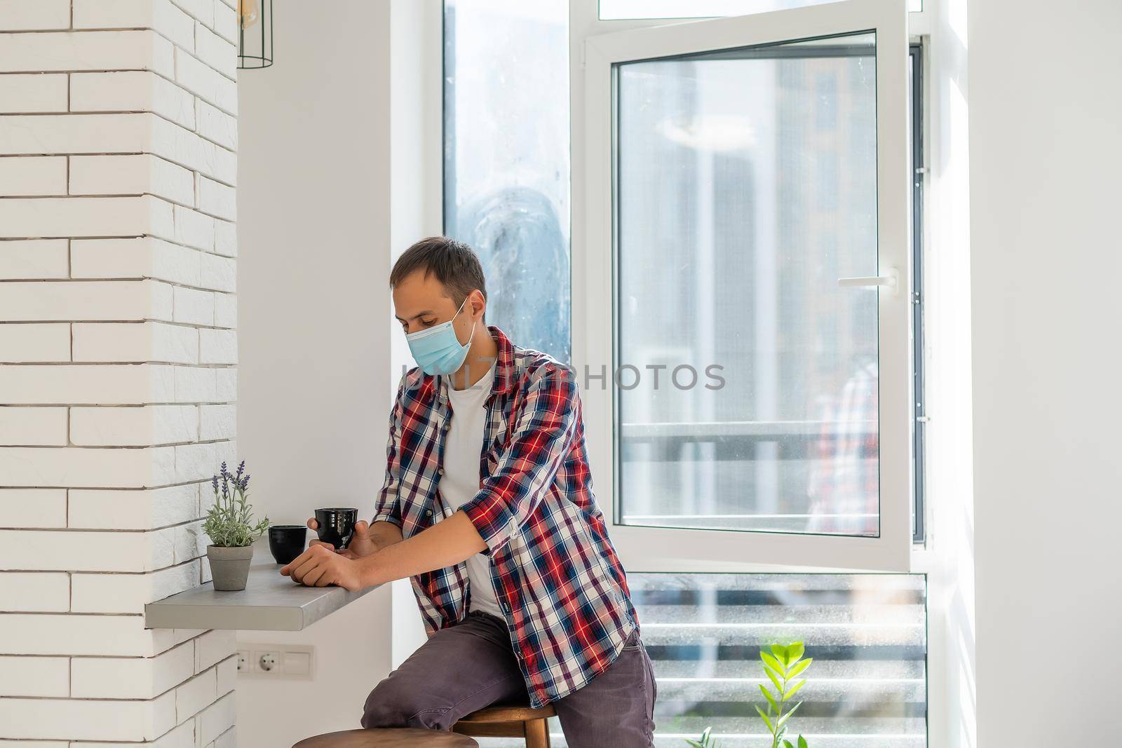 man with face mask serving coffee through window, shop open after lockdown.