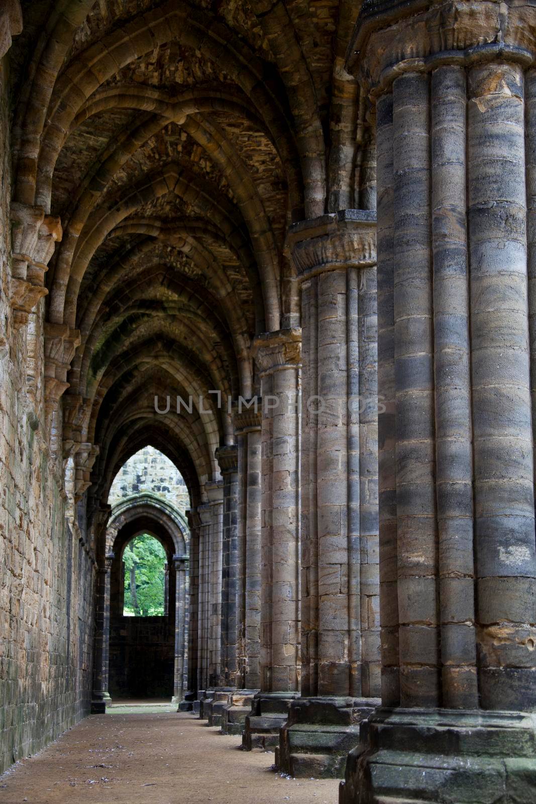 Symetrical aged gothic cloisters leading to a doorway