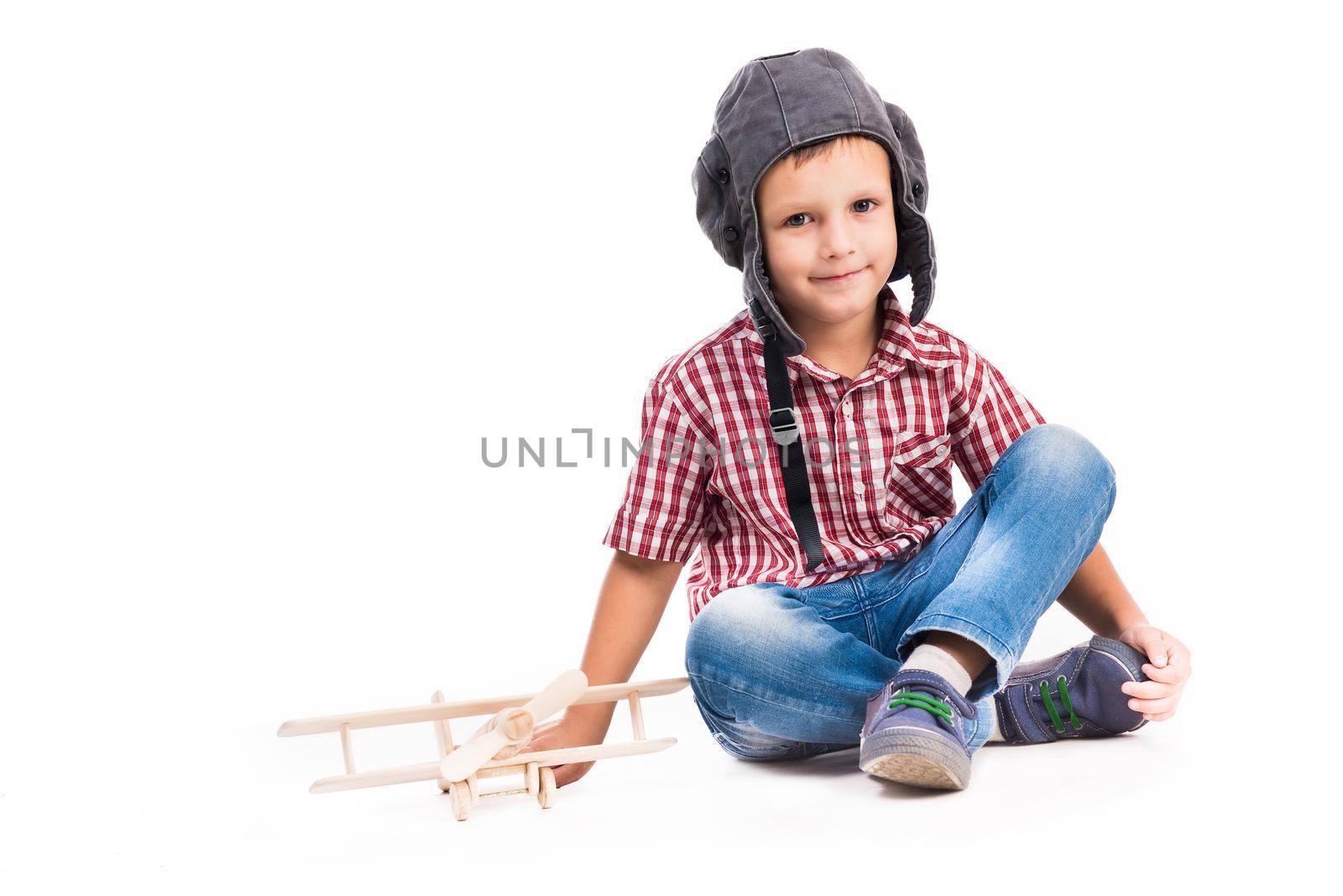 little boy with pilot hat and toy airplane sitting isolated on white background