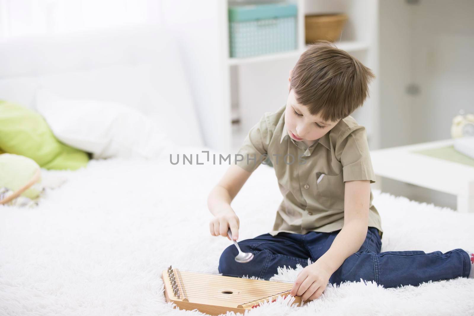 A child with a musical instrument. Boy learn to play dulcimer