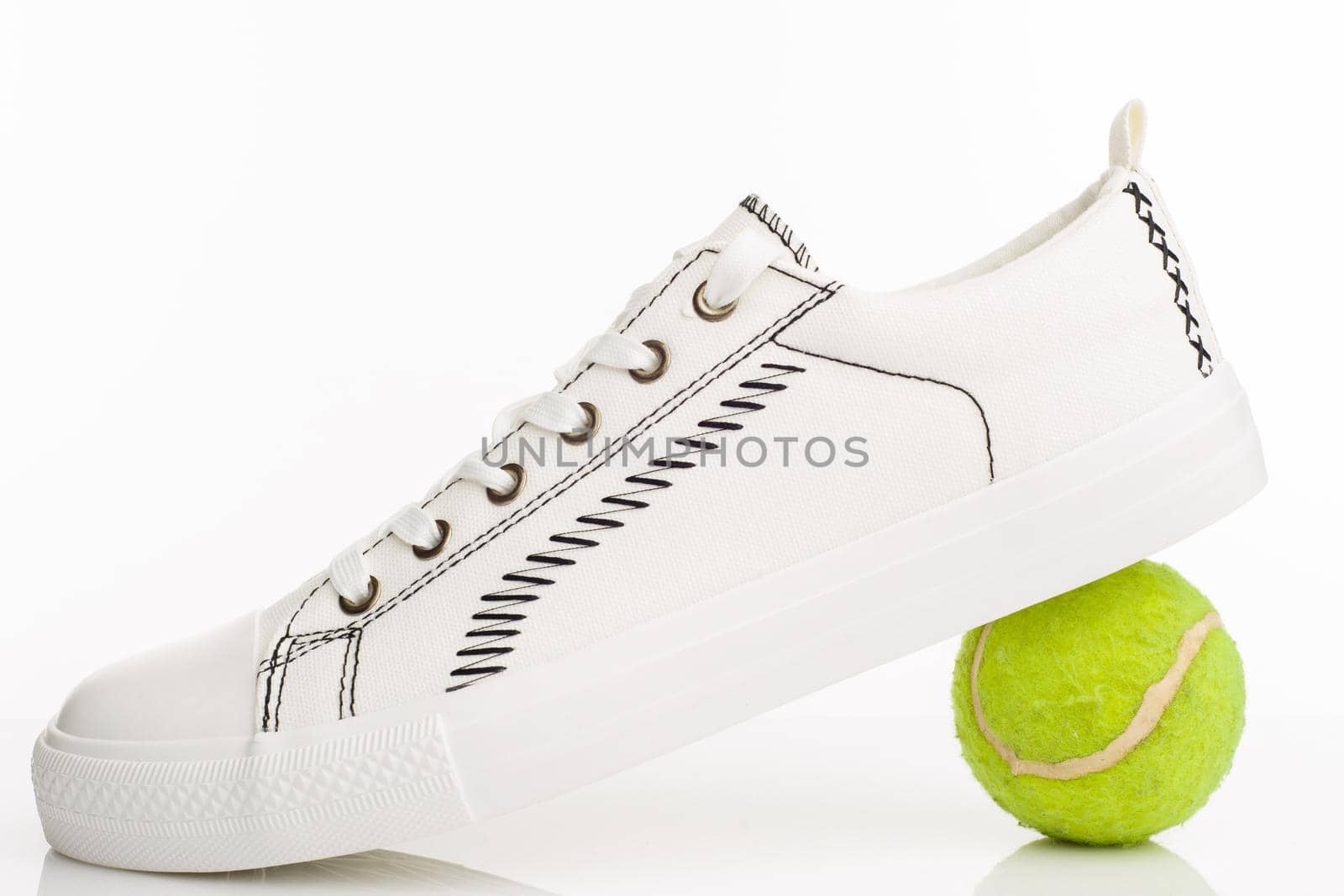 Fashionable white walking shoes with tennis ball on a white background. - image