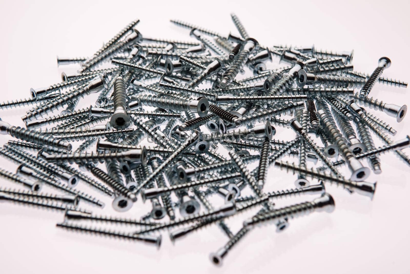 Mound of furniture screws top view on white background- image