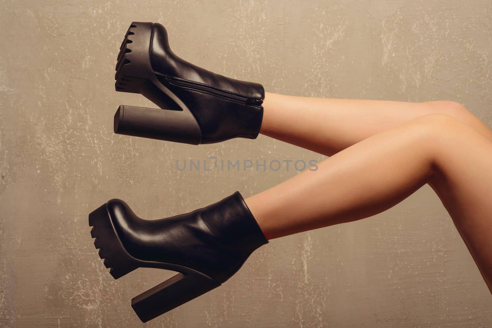 beautiful female feet in ankle boots near wall
