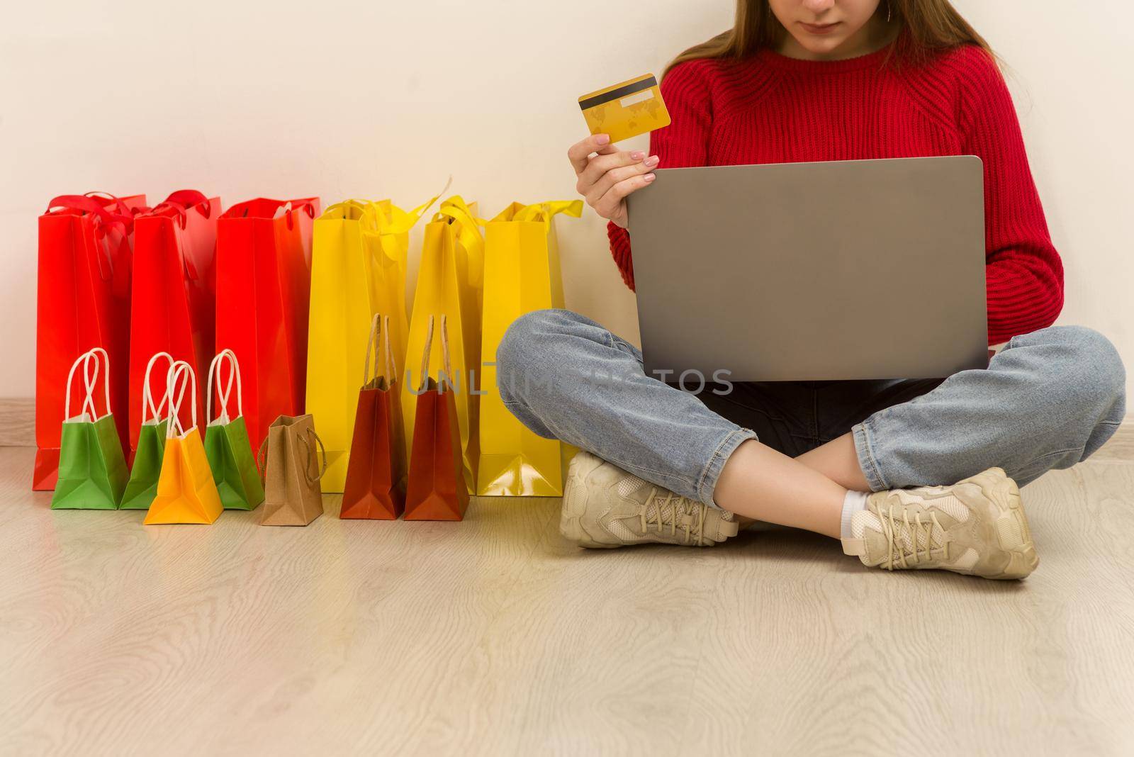 Young woman doing online shopping at home using laptop. Happy satisfied customer with purchase