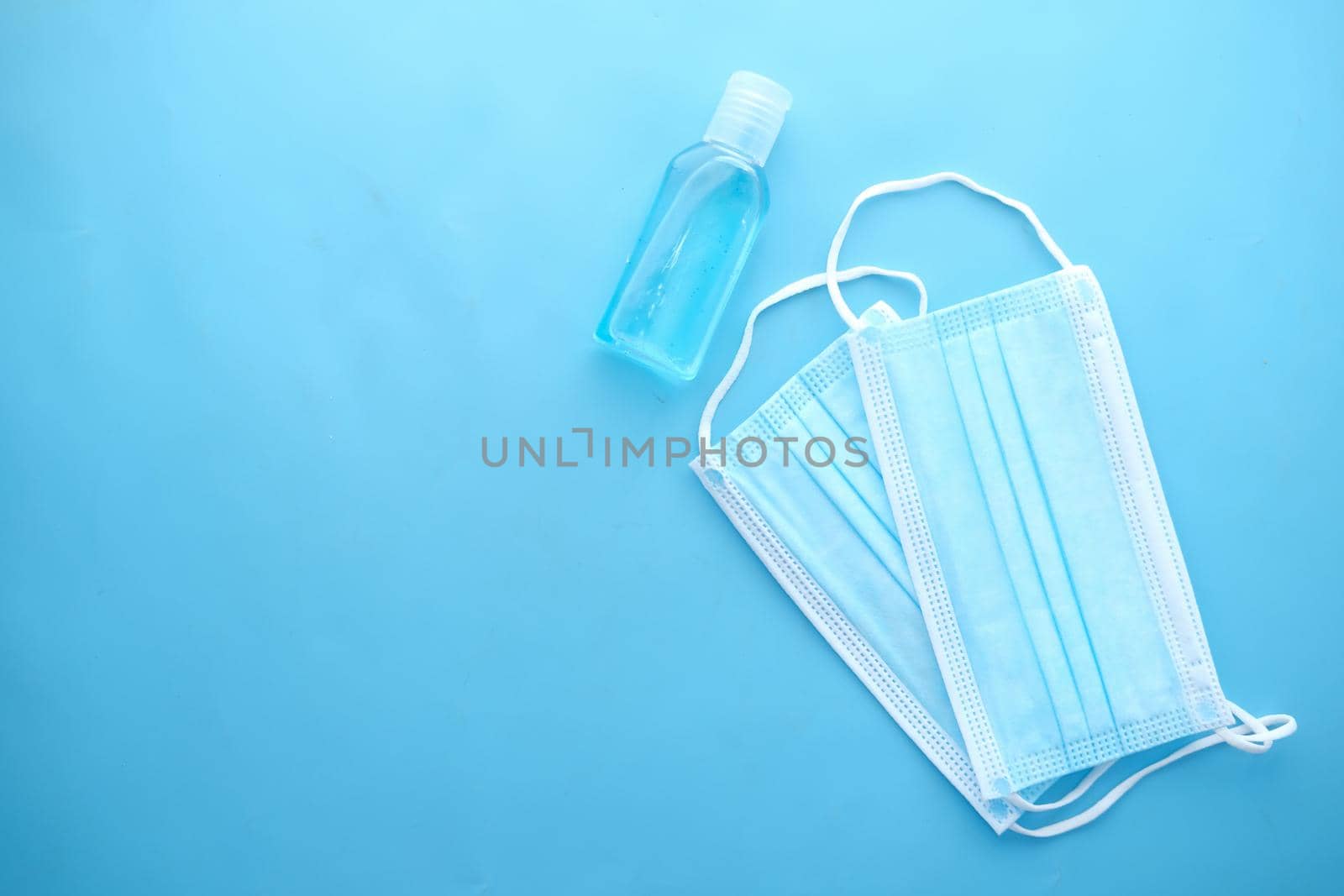 Surgical masks, and hand sanitizer on blue background .