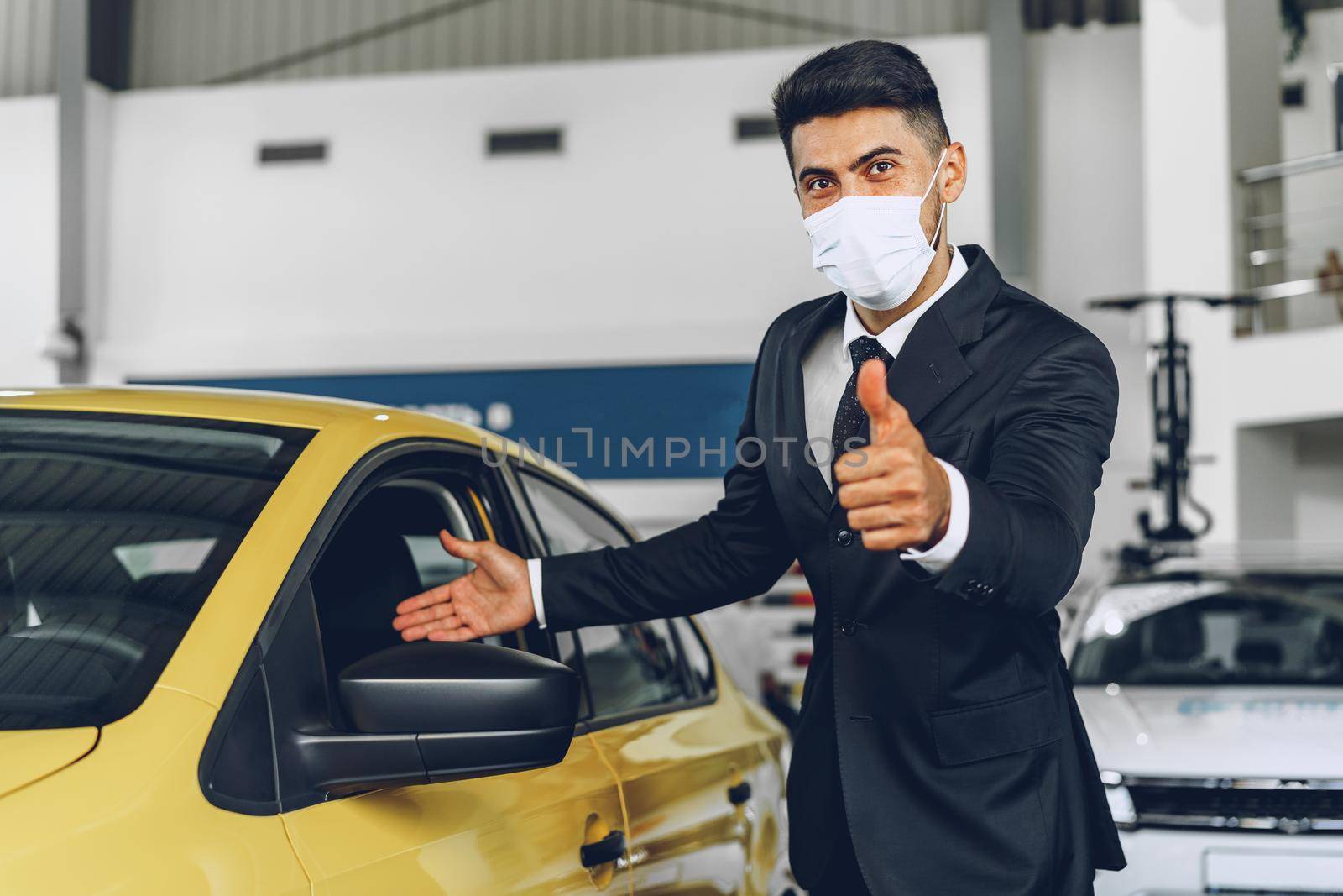 Man car dealer wearing protective medical mask on his working place, coronavirus prevention concept
