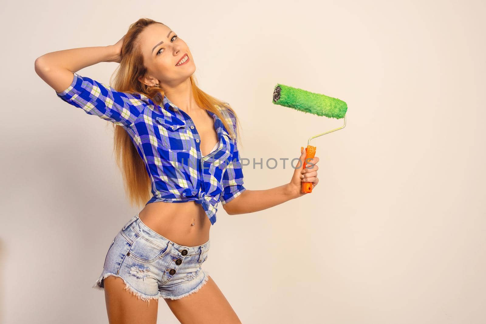 pretty young smile redhead lady with green paint roller isolated on background.