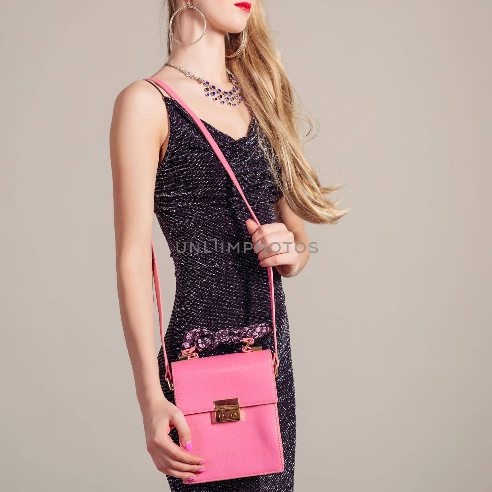 slim trendy woman in evening dress with pink bag in hands and stylish necklace by zartarn