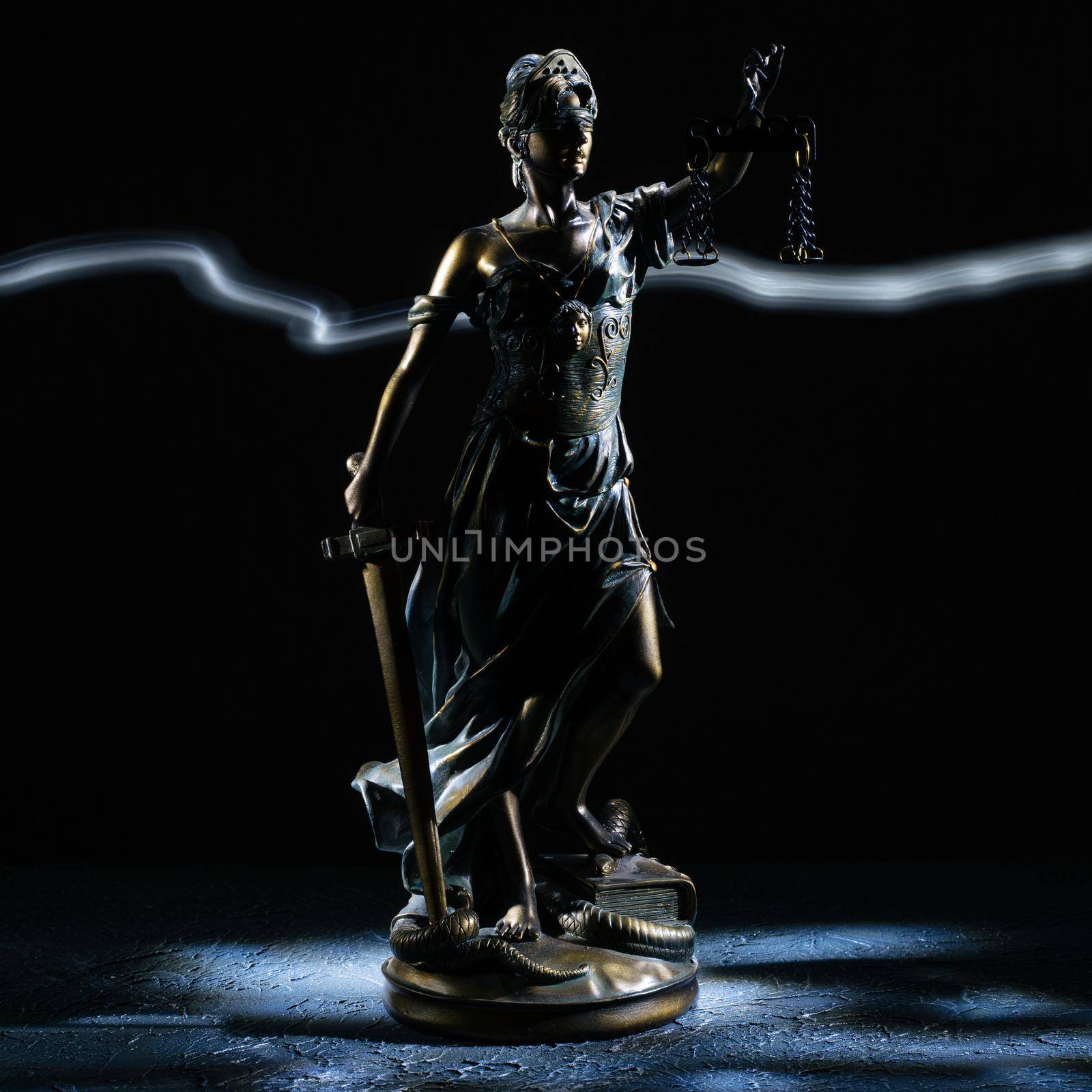 Themis statuette stands on the old vintage stone table. Picture taken with a light brush - Image