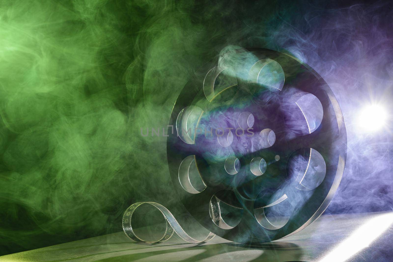 Metal reel of film is in the smoke at the table